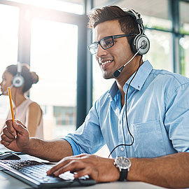 Contact personnel avec LANCOM Personnel de vente amical avec casque répondant aux appels des clients au bureau